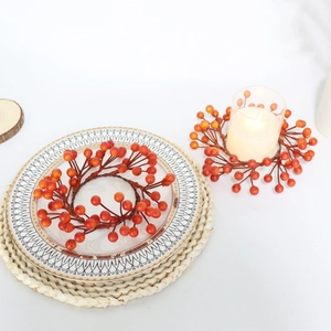 Detail of orange berry candle ring on a rustic table setting for seasonal decoration