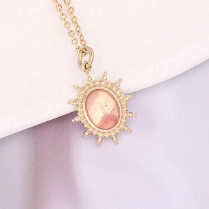 Macro view of gold stainless steel necklace with sunburst oval natural stone pendant