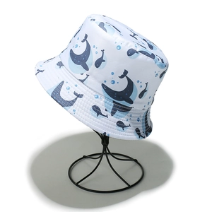 Close-up of white cotton bucket hat with blue whale print and stitched brim details