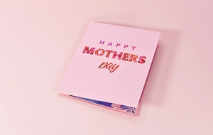 Close-up of a pink Mother's Day 3D greeting card with floral 'HAPPY MOTHERS' typography