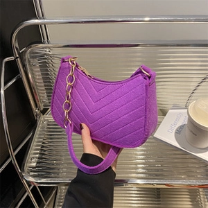 Detail of purple bucket bag featuring V-shaped quilting and elegant metal chain strap