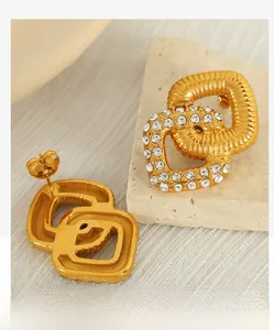 Detail of gold interlocking square earrings with sparkling crystals on textured stone