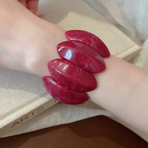Macro shot of dark red acrylic stretch bracelet featuring unique marbled resin texture