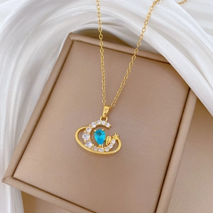 Detail of gold crescent moon and star necklace with blue teardrop gemstone and zircons