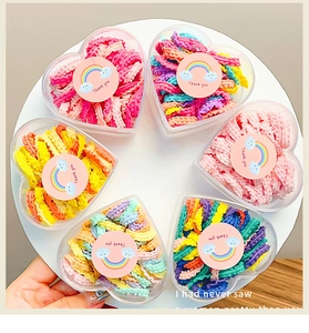 Macro view of colorful elastic wavy hair ties in heart-shaped clear gift boxes