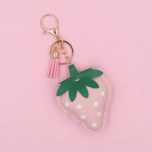 Detailed view of a pink strawberry leather keychain with green leaves and tassel decoration