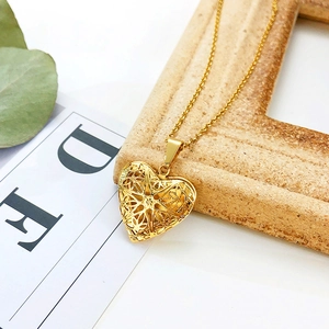 Detail of a gold heart-shaped locket necklace with intricate hollow carvings on wood