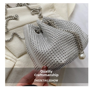 Detail of silver rhinestone bucket bag featuring metallic chain and pearl pendant