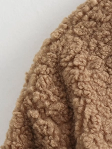 Dettaglio della spessa texture in pile teddy kaki di una giacca corta con scollo a V