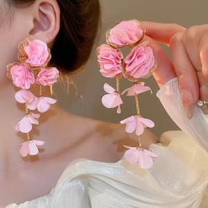 Close-up of pink fabric floral petal tassel earrings worn by a model in soft lighting