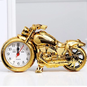 Golden motorcycle shaped alarm clock with quartz dial on white background