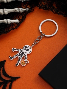 Detail of Halloween skull keychain with orange pumpkin lantern on spooky background