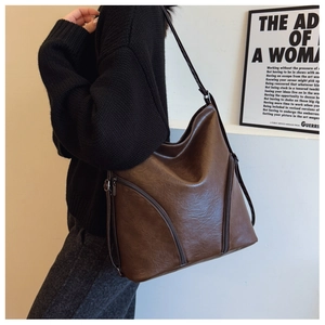 Side view of dark brown oversized leather tote bag showing drape and capacity on model