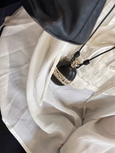 Detail of egg-shaped wood pendant with silver metal overlay on black cord necklace