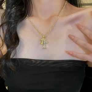 Close-up of a gold-plated cross necklace with sparkling rhinestones on a female model