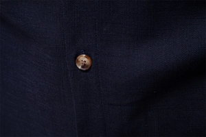 Macro shot of navy blue shirt fabric texture with a marbled brown button detail