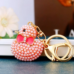 Macro shot of pink pearl duck keychain with enamel bow and gold metal ring detail