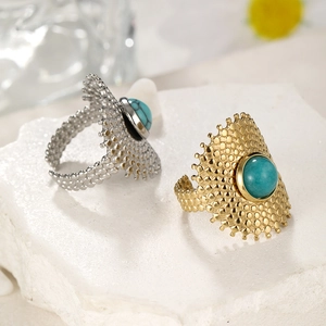 Detail of gold and silver rings with turquoise stones on a white textured stone base