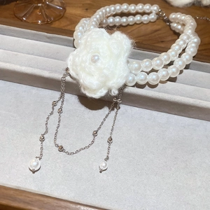 Détail d'un collier de perles à deux rangs avec fleur tricotée et pampilles à franges