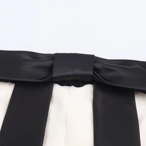 Vista dettagliata del fiocco di raso nero lucido sull'elegante abito a fascia bianco e nero