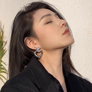 Boucles d'oreilles cœur argentées ajourées avec zircon portées par un mannequin asiatique