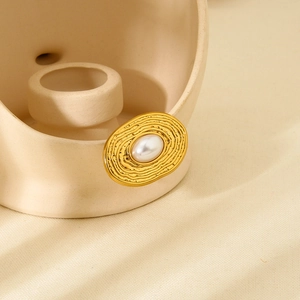 Detailed close-up of 18K gold plated ring with white pearl and shell texture on ceramic