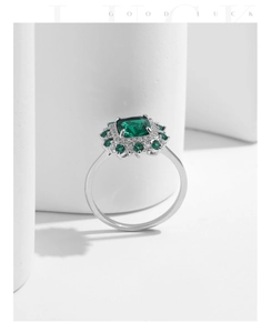 Macro detail of rectangle emerald ring with sparkling halo and elegant Good Luck script