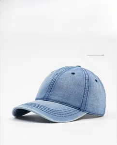Detail of light blue washed denim baseball cap showing top eyelets and stitched brim