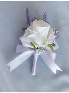 Detail of white artificial rose boutonniere with purple accents and white silk ribbon