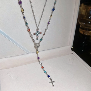 Detail showing double-layer silver cross necklace with vibrant colorful gemstones