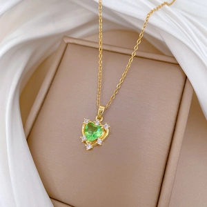 Gold titanium steel necklace with green heart zirconia pendant on silk background