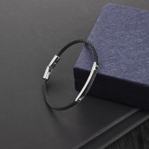 Detail of steel wire bracelet showing a silver buckle with stainless steel engraving