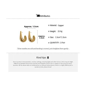 Macro detail of golden copper teardrop earrings featuring silver pins and smooth curved surface