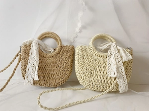 Detail view of woven straw basket bags with lace ribbons in natural and cream white colors