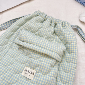 Close-up of heart-shaped quilting and blue gingham pattern on a drawstring backpack detail