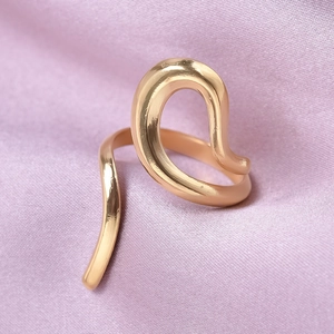 Macro detail of golden irregular geometric open ring on elegant purple silk fabric