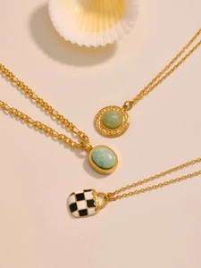 Detailed close-up of gold necklaces with emerald stones and checkered pattern on shells