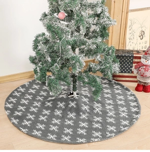 Gray plush Christmas tree skirt with white snowflake patterns in a cozy festive setting