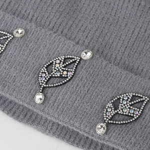 Macro detail of leaf-shaped rhinestones on a gray knit beanie with crystal accents
