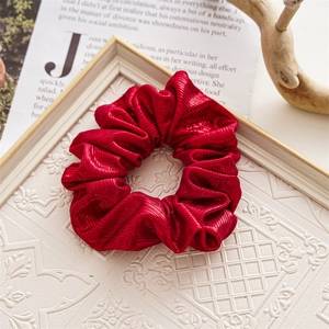 Detail of red wrinkled fabric scrunchie on vintage book page with white frame