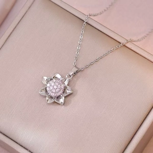 Detailed close-up of a rotating silver flower pendant with pink zircon in a silk jewelry box