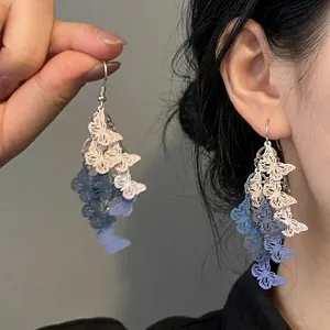 Macro shot of blue and white gradient butterfly tassel earrings with hollow metal design