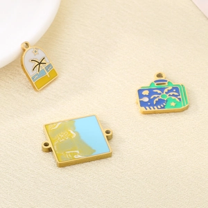 Macro view of three gold-plated enamel pendants featuring palm trees and beach sunsets