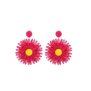 Detailed view of handmade woven raffia flower earrings in vibrant magenta and yellow