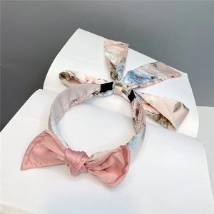 Detail view of pink floral satin headband featuring a sweet bow and long flowing streamers