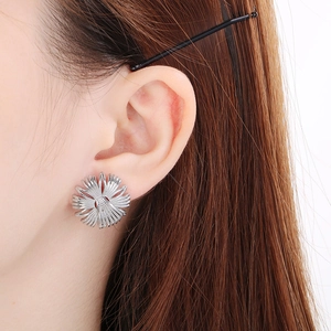 Detailed view of a silver geometric starburst earring worn on a model's earlobe
