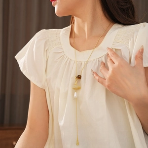 Tiger eye cross teardrop pendant necklace with pearls on a golden long chain worn by model
