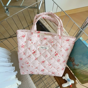 Pink floral quilted cotton handbag styled in a wire basket with soft lifestyle props