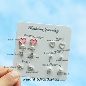 Detailed view of six-pair earring set with dimensions on card under blue sky