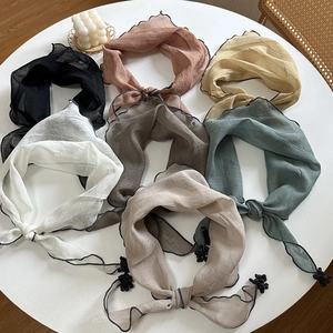 Flat lay of colorful thin scarves with wavy edges and pompom details on white background